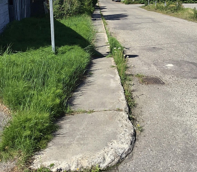 A photo of the existing conditions along 4th Avenue shows a sidewalk without a curb ramp, grassy vegetation encroaching on the sidewalk, and concrete that is chipped and deteriorating. 
