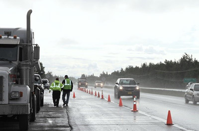 Commercial Vehicle Enforcement Officers inspect a truck, near Fairbanks